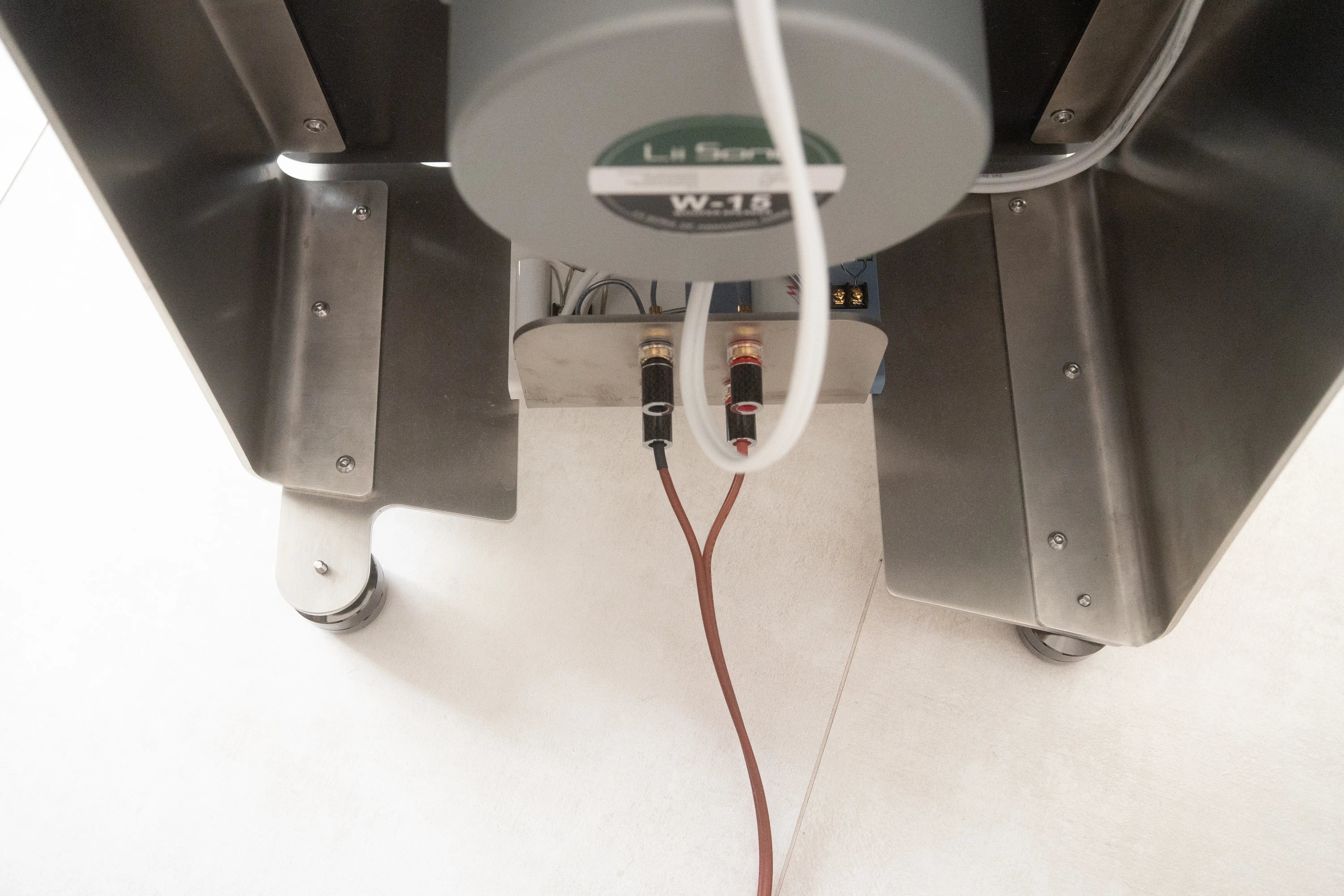 Bottom view of the speaker showing the W-15 woofer label on the magnet and the dual binding-post connectors with their copper cables routed out from the base.